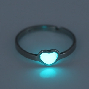 Detail showing an open stainless steel ring with a glowing blue heart in the dark