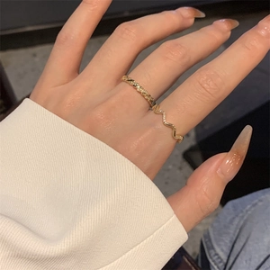 Close-up of gold-plated twisted rope and wavy cubic zirconia rings on model finger