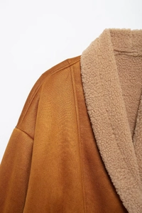 Detailansicht des beigen Lammfellkragens und der braunen Wildlederstruktur der Jacke