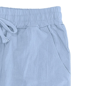 Detailed close-up of light blue linen trousers with elastic drawstring waist and side pockets