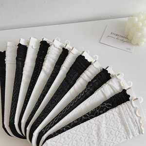 Close-up of black and white lace mesh socks with floral patterns and ruffled edges