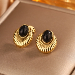 Macro detail of retro gold earrings with black oval gemstone and ribbed texture