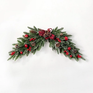Christmas wreath with green pine needles, red berries, pine cones and red plaid bow tie