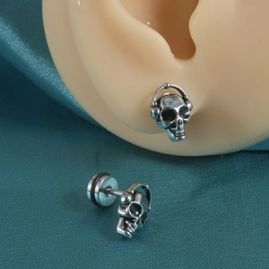 Détails des boucles d'oreilles punk crâne avec casque sur modèle d'oreille et satin