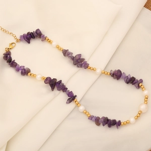 Elegant natural purple crystal and pearl necklace on beige silk fabric background