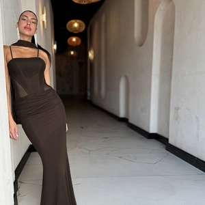 Dark brown corset mermaid maxi dress with sheer mesh panels in a minimalist setting