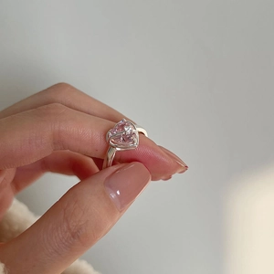 Close-up of pink heart gemstone ring set in polished silver band on woman's finger