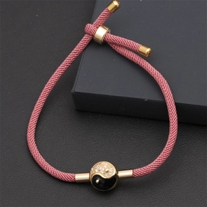 Detailed view of pink woven bracelet with gold Yin Yang charm and sparkling crystals