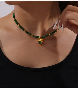 Gros plan d'un collier de perles vertes avec pendentif en cœur doré sur un mannequin