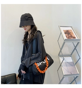 Détail du sac cylindrique en nylon avec chaîne orange vif et imprimé sport blanc