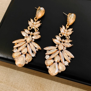 Gros plan détaillé des boucles d'oreilles en cristal champagne sur fond texturé