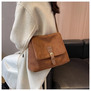 Borsa a tracolla in pelle scamosciata marrone con fibbia in metallo su cappotto beige