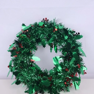 Detail of green metallic Christmas wreath with red berry accents and festive decorations