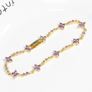 Elegant gold flower bracelet with purple zircon stones on white ceramic plate
