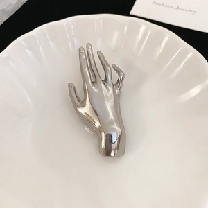 Macro shot of silver hand brooch showing mirror polished finish and metal details