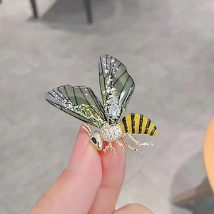 Elegant gold-tone bee brooch with sparkling crystals and yellow enamel detail on hand