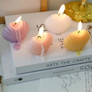 Scented shell-shaped candles in pastel colors burning on a decorative book stack