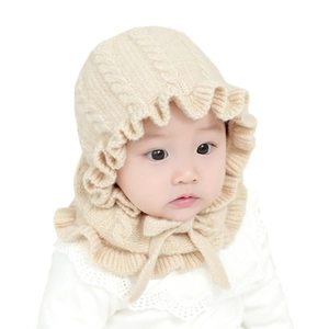 Knitted baby bonnet with ruffle trim and cable pattern in soft cream color