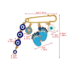 Detailed view of evil eye safety pin brooch with Hamsa hand and cross charms