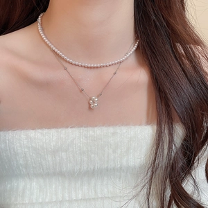 Close-up of double-layer French pearl necklace with floral pendant on a female model