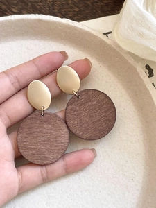 Detail of vintage earrings with gold oval metal and dark brown round wood textures
