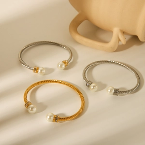 Detail of twisted cable bangles in gold and silver finish with pearl and crystal ends