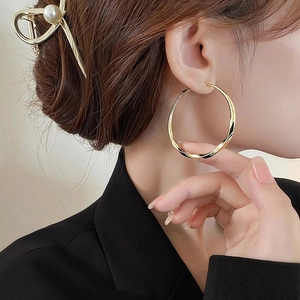 Elegant gold large hoop earrings with twist texture design shown on model's profile