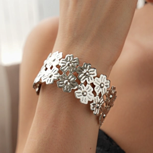 Detailed view of silver flower hollow-out bracelet on wrist with elegant daisy design
