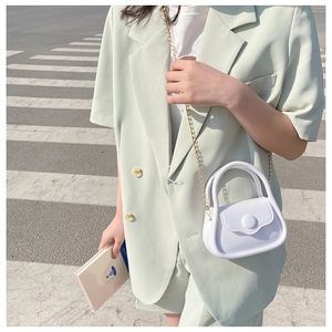 Action shot of a mini white jelly bag with gold chain strap on a green suit outfit