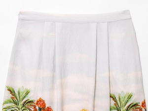 Detailed macro view of tropical palm tree and floral print on pleated midi skirt fabric