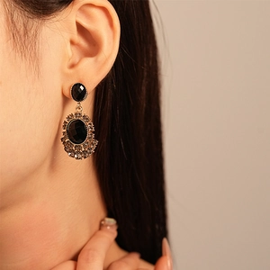 Vintage gold sunflower drop earrings with black rhinestones worn by a model