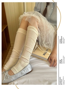 Detail of balletcore cream rib-knit leg warmers with delicate ribbon bow and ballet flats