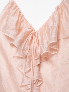 Close-up of pink V-neck dress featuring ruffled edges and textured pearlescent fabric