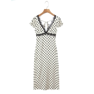 Detail view of V-neck polka dot dress featuring elegant black lace trim on cream fabric