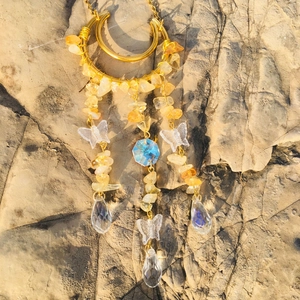 Close-up of golden wire moon suncatcher with yellow crystals and glass drops on stone