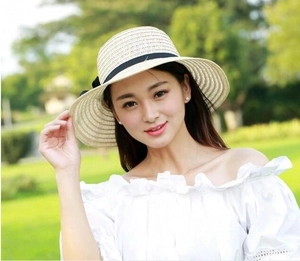 Dettaglio di cappello da sole in paglia da donna con fiocco nero e trama traforata