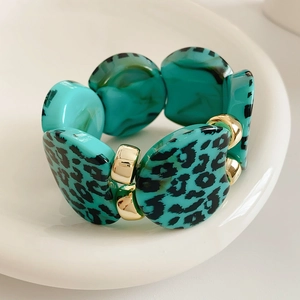 Detailed close-up of green leopard resin links and gold metal beads on a bracelet