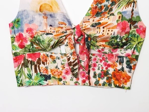 Detail of tropical landscape print and front knot design on a cropped women's top