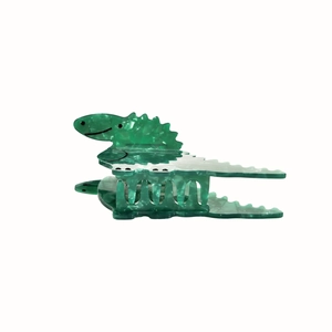 Detailed view of a green dinosaur hair claw clip made of transparent acetate material