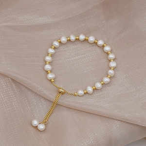 Close-up of natural freshwater pearls and gold beads on elegant silk fabric texture