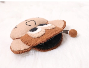 Close-up of a brown felt monkey coin purse with zipper opening on a soft white plush background