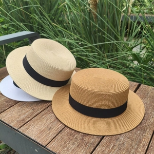 Klassische Strohhüte in Weiß, Beige und Khaki mit schwarzen Bändern auf einer Holzbank