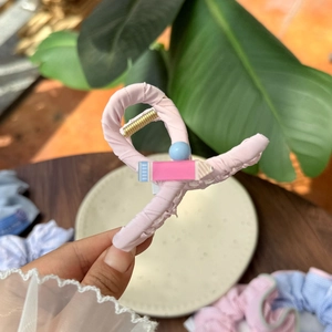 Pink fabric hair claw clip with cute pencil design and blue beads held in hand