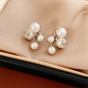 Macro view of cluster pearl earrings with silver textured base on champagne satin lining