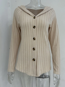 Dettaglio di felpa beige in maglia a coste con cinque bottoni ambrati e cappuccio