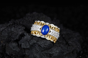 Detailed macro view of wide retro hollow ring with blue gemstone on black rock surface