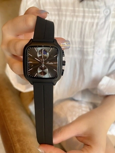 Close-up of black square watch with silicone strap and chronograph dials on a female wrist