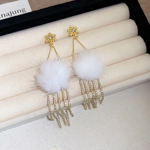 Detail of gold snowflake earrings with white fur balls and sparkling rhinestone tassels