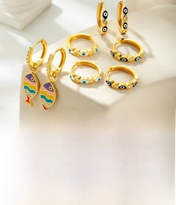 Detail of Bohemian gold hoop earrings with enamel fish and evil eye charms