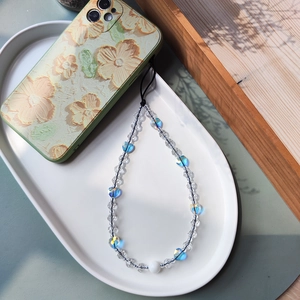 Detail of beaded phone strap with transparent, blue heart and white beads on floral phone